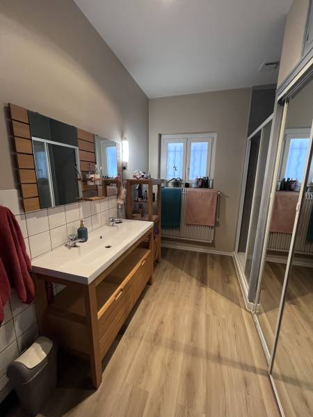 Notre technicien qualifié à rénover une salle de bain moderne avec un parquet en bois, meuble vasque, mitigeur et miroir 