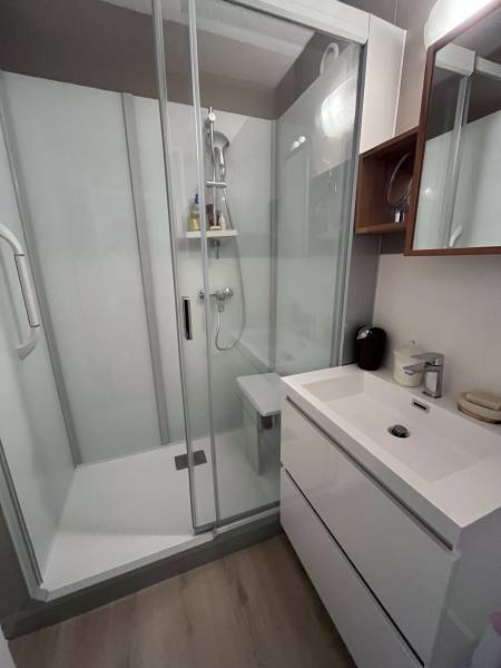 Salle de bain PMR aménagé avec douche à l'italienne, barre d'appui, siège et revêtement anti-dérapant